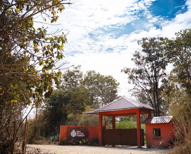 Main entrance gate of Saj in the Forest resort with the resort signage set amidst bare trees in Pench, Madhya Pradesh.