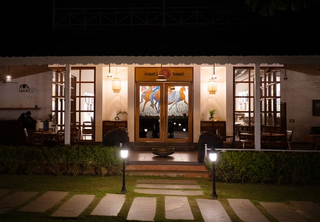 Warmly illuminated exterior of Maati Baani restaurant at Saj in the Forest, Pench, glowing at night with elegant lanterns.