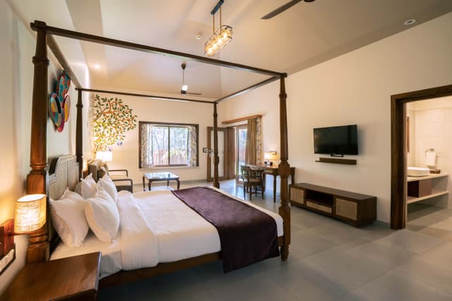 Spacious suite at Saj in the Forest with a four-poster bed, nature-inspired wall art and forest views through the window.