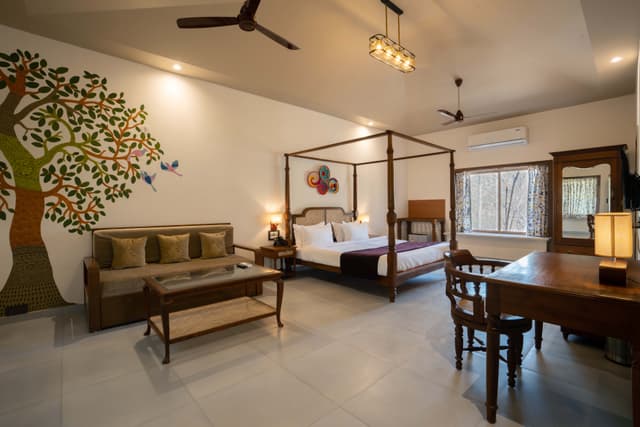 Generously appointed room at Saj in the Forest with a four-poster bed, hand-painted tree mural and traditional wooden furniture.