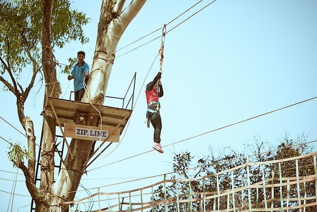 Guest enjoying ziplining at Saj On The Mountain, a resort in Mahabaleshwar with activities.