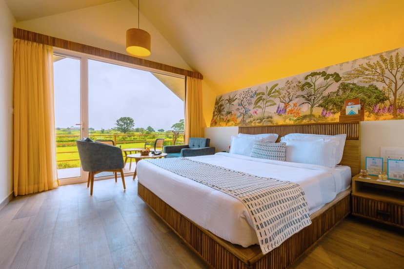 Bright and airy guest room at Saj By The Lake with a king bed, floral wall art headboard and large balcony doors opening to green lawns.