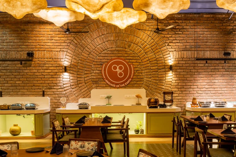 Feature wall of Maati Baani restaurant at Saj By The Lake with a circular brick arch and the Language of the Earth brand logo.