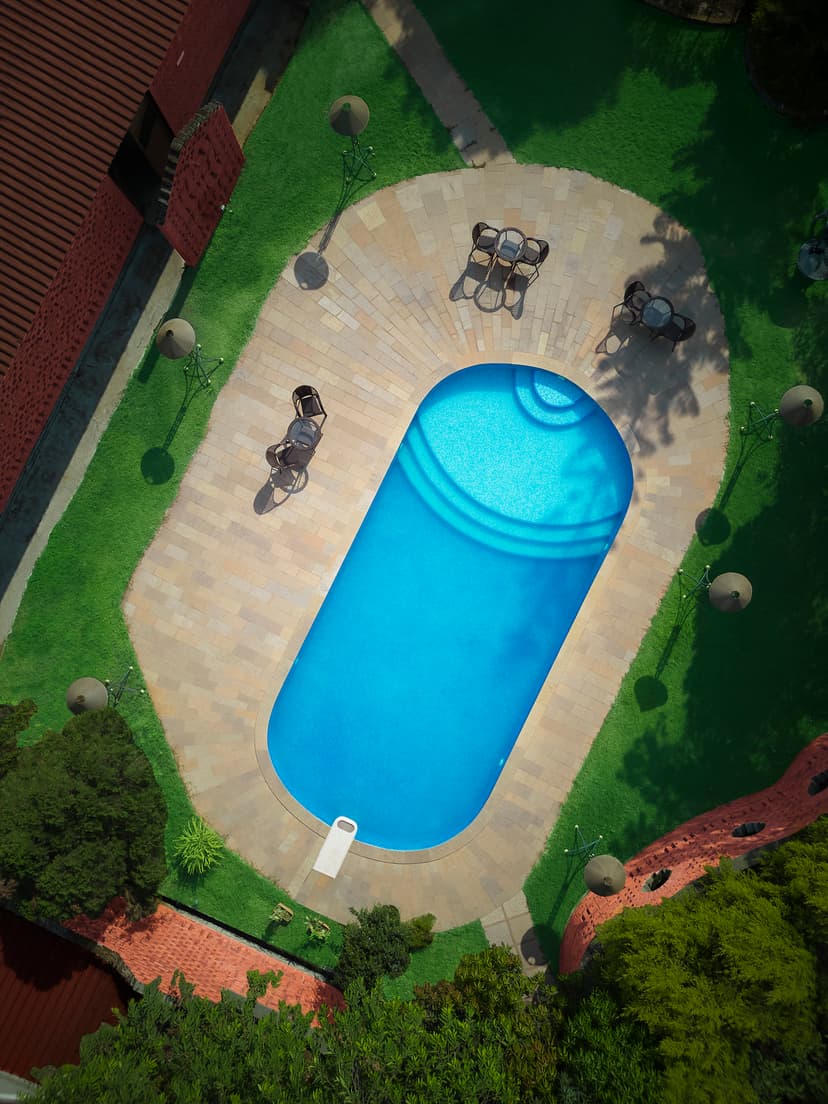 Top-down aerial view of the outdoor swimming pool at Saj By The Lake surrounded by manicured green lawns.