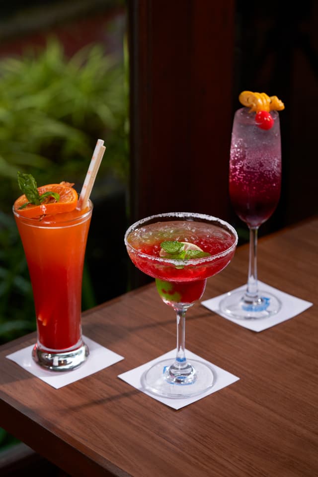 Three colourful cocktails served on a wooden bar counter at Saj By The Lake resort, Malshej Ghat.