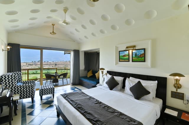 Bright and airy lake view room at Saj By The Lake with a king bed and a balcony offering panoramic views of the lake and Sahyadri mountains.